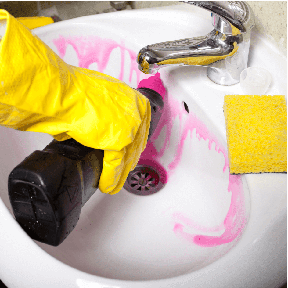 Gloved hand cleaning a bathroom sink with a sponge